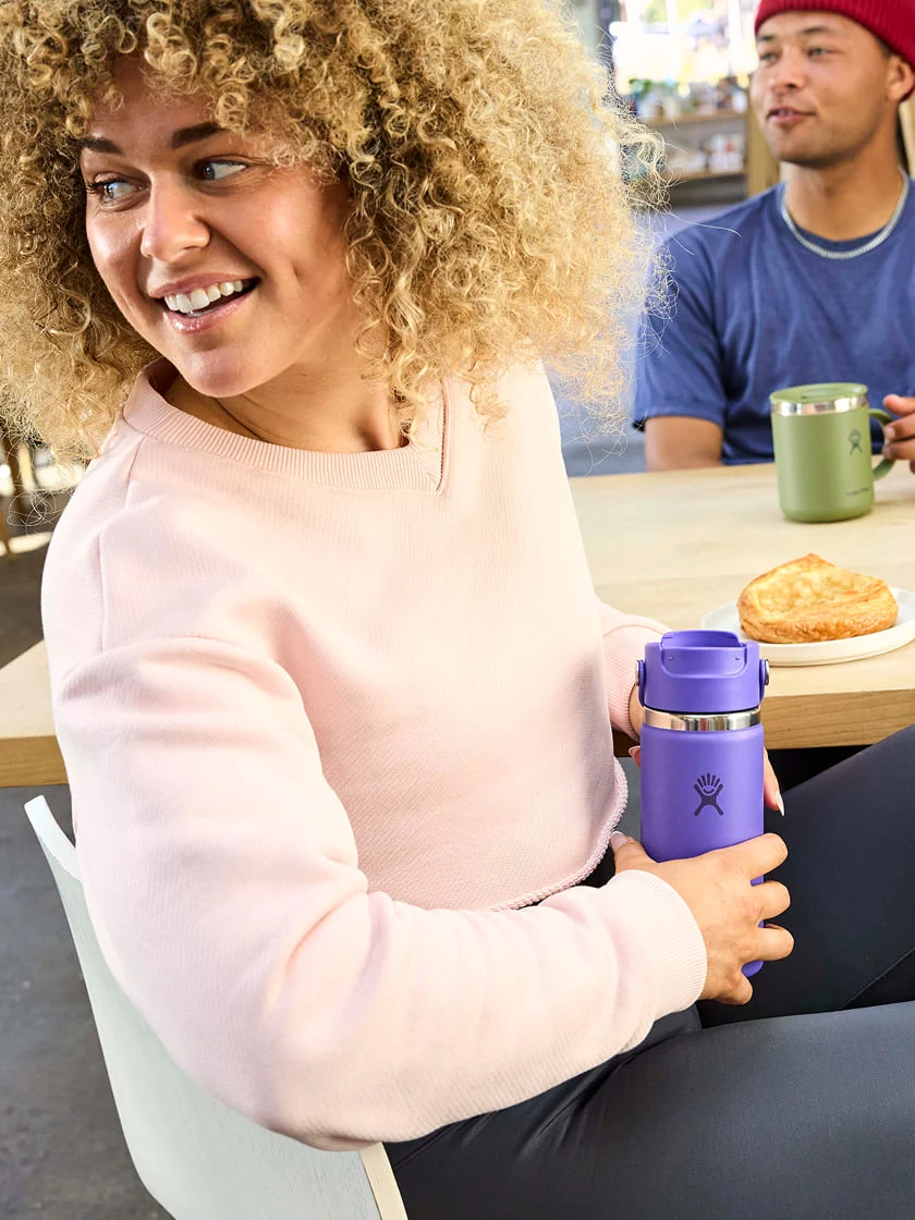 female holding a purple flip sip travel mug at a coffee shop