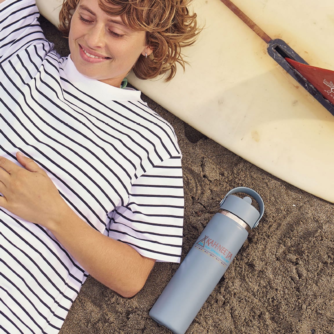 Girl laying on a surfboard with a custom printed Hydro Flask