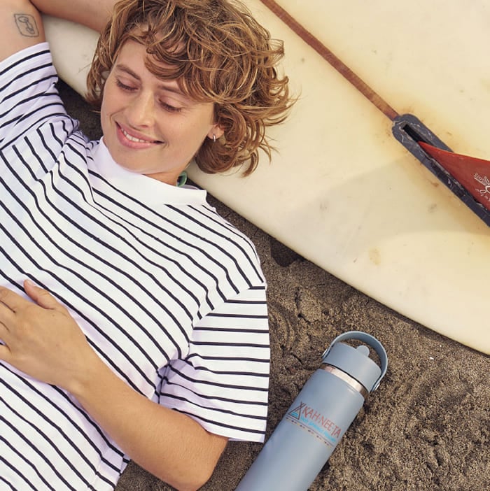 Girl laying on a surfboard with a custom printed Hydro Flask