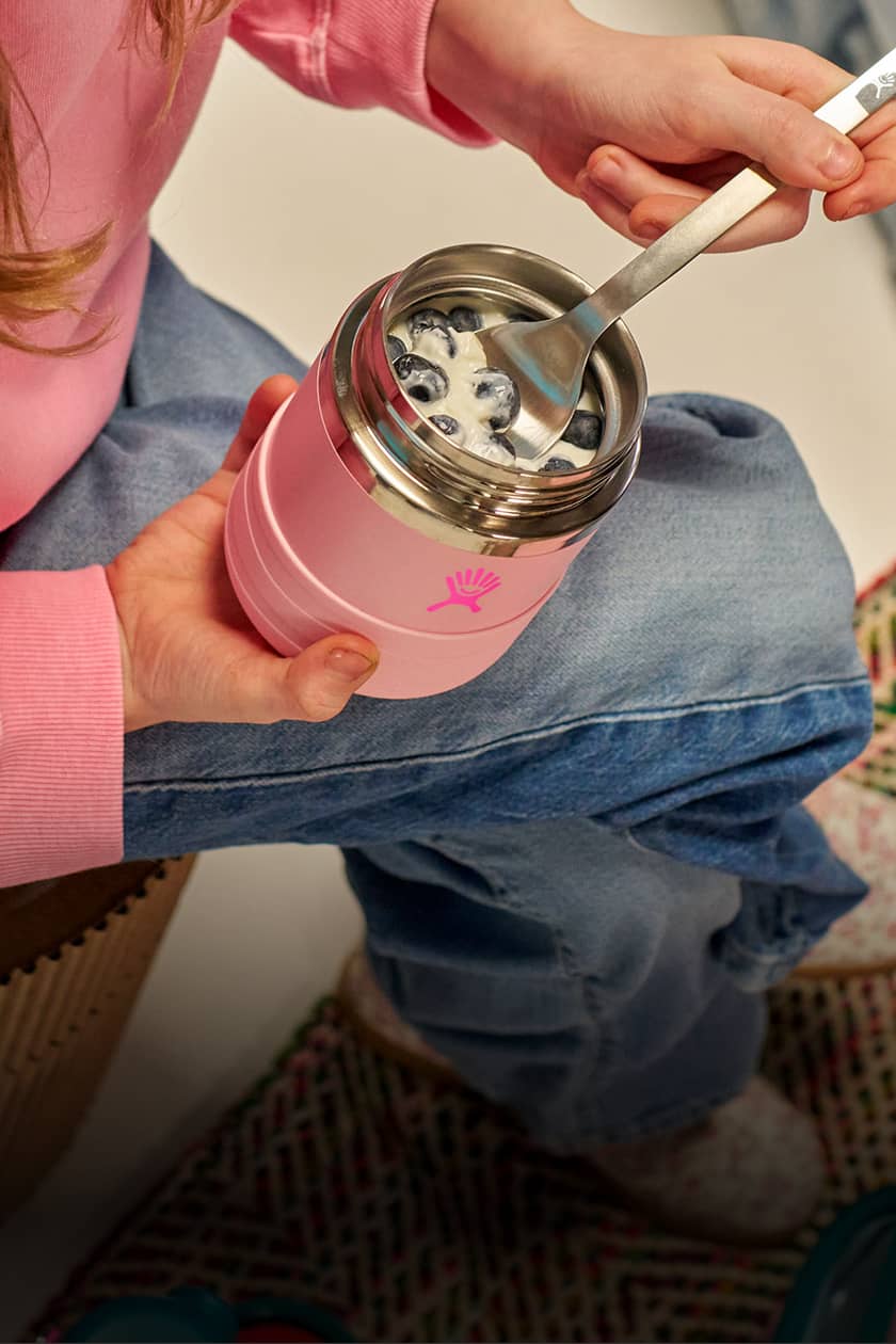 girl holding hydro flask kids food jar and spoon for cereal