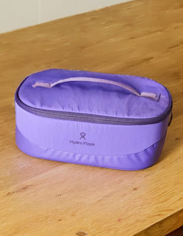 A Hydro Flask Utopia Purple Carryout&trade;&nbsp;Lunch Box sitting on a wooden table