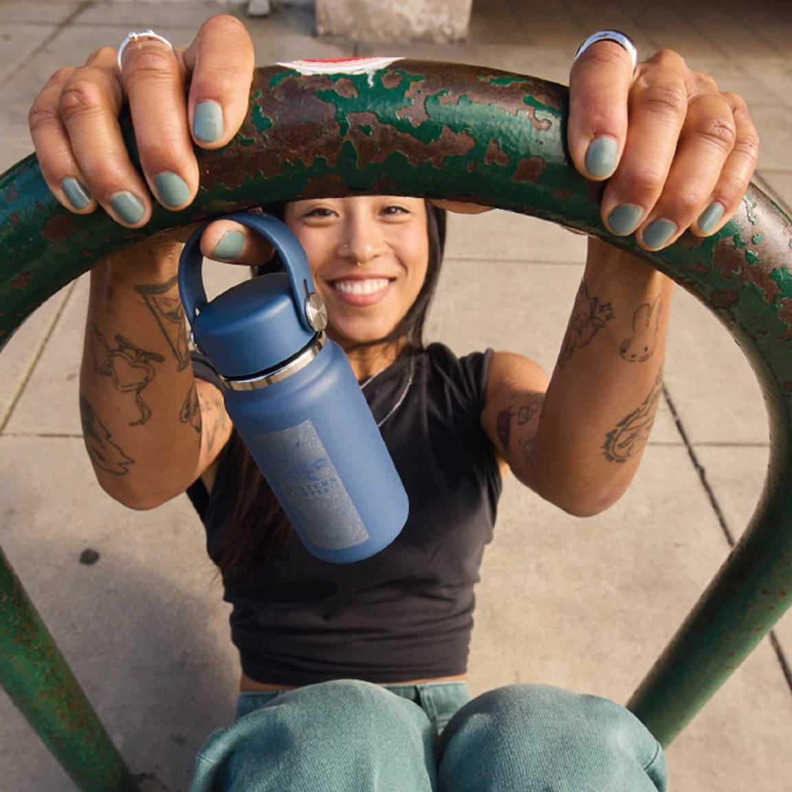 Girl swinging on a concrete bike rack holding a Hydro Flask Micro Hydro with a custom company engraving