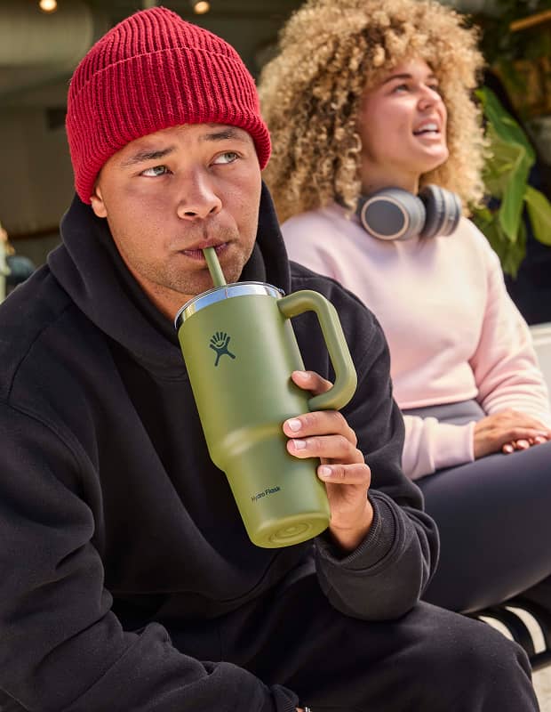Man drinking out of a green hydro flask travel tumbler