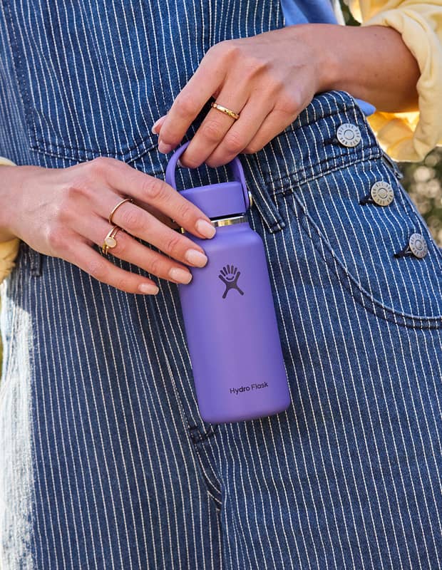 close up of a hand holding a purple micro hydro in front of blue striped overalls