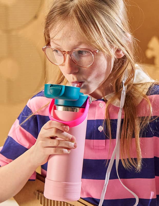 Girl with glasses drinking out of a Hydro Flask Kids bottle with the new covered cap