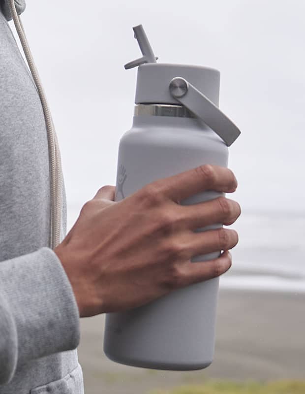 Man on beach holding a Birch Hydro Flask straw bottle