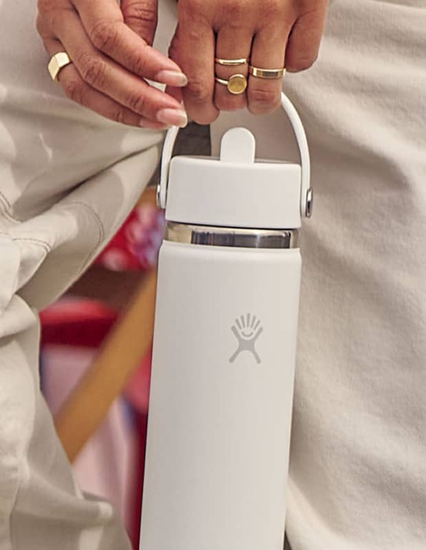 Person holding a white Hydro Flask straw bottle wearing matching white pants