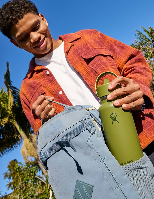 Boy pulling a 32 oz Palmer Green Hydro Flask out of a backpack side pocket